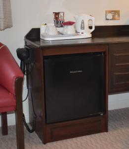 a television sitting on a desk with a telephone at Peartree Lodge Waterside in Milton Keynes