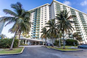 a large building with palm trees in a parking lot at Sunny Isles Ocean Reserve Superb Condo Apartments in Miami Beach
