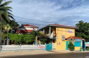 a yellow and blue house with a white fence at All Seasons Belize in Hopkins