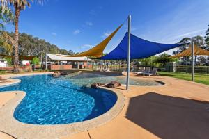 una piscina con una sombrilla azul y amarilla en Discovery Parks - Maidens Inn Moama, en Moama