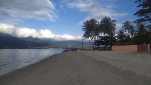 - une plage avec des palmiers, de l'eau et des montagnes dans l'établissement Casa com Piscina 200 m da Praia - São Sebastião, à São Sebastião