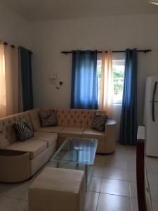 a living room with a brown couch and blue curtains at Apartamentos y Villas Michaela in Sosúa