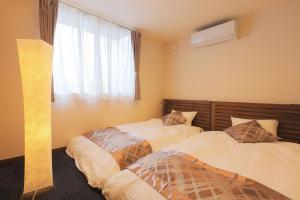 a bedroom with two beds and a window at Villas Asama no Iori in Fujiyoshida