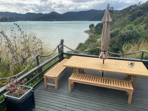 a wooden deck with an umbrella and a bench at Pacific Harbour Lodge in Whangaroa