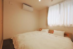 a bedroom with a bed with white sheets and a window at Villas Asama no Iori in Fujiyoshida