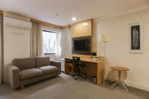 ein Hotelzimmer mit einem Sofa, einem Schreibtisch und einem TV in der Unterkunft (103)Flat Executive Jardins (Apt. particular) in São Paulo