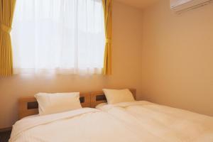 two beds in a room with a window at Villas Asama no Iori in Fujiyoshida