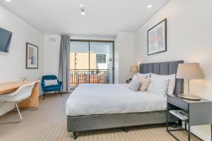 a bedroom with a large bed and a desk and a desk at All Suites Perth in Perth