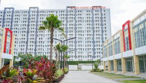 a large white building with palm trees in front of it at Apartemen Taman Melati Yogyakarta by ArFe Room in Sleman