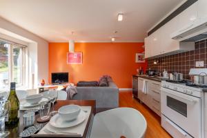 a kitchen and living room with an orange wall at First Tracks by H2 Life in Niseko