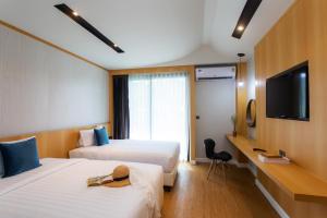 a hotel room with two beds and a flat screen tv at The Canale Samui Resort - SHA Extra Plus in Chaweng