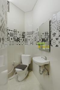 a white bathroom with a toilet and a sink at House of Asiyah Syariah in Solo