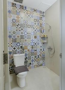 a bathroom with a toilet and a mosaic wall at House of Asiyah Syariah in Solo