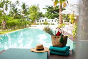 a table with towels and a hat next to a swimming pool at The Canale Samui Resort - SHA Extra Plus in Chaweng