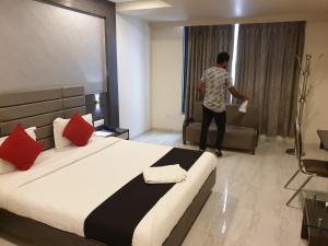 Ein Mann steht in einem Hotelzimmer mit einem Bett in der Unterkunft Hotel Unity in Ahmedabad