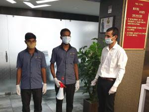 three men wearing masks standing in a lobby with aumed at Hotel Unity in Ahmedabad