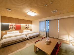 a bedroom with a large bed and a table at Kyoto Central Inn in Kyoto