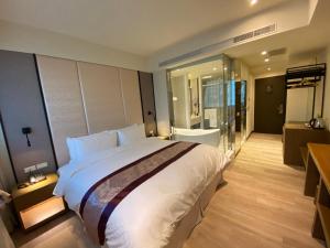 a bedroom with a large bed and a bathroom at Cai Mei Hotel in Dahu