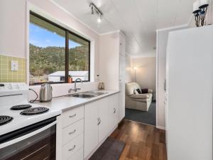 a kitchen with white cabinets and a large window at Relax Lakeside - Lake Rotoiti Bach in Rotoiti