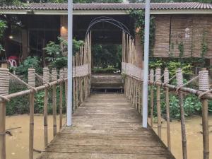 a wooden walkway leading to a building with a bridge at Promma Farm Resort in Ban Tat Ton (1)