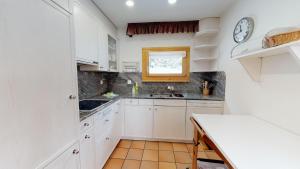 a kitchen with white cabinets and a clock on the wall at Abitaziun Trais Tschiervs D5 - Champfèr in Champfer