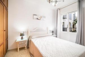 ein weißes Schlafzimmer mit einem Bett und einem Fenster in der Unterkunft Apartamento Conil Centro in Conil de la Frontera