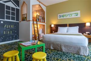 a bedroom with a bed and two chairs and a desk at Holiday Inn Melaka, an IHG Hotel in Melaka