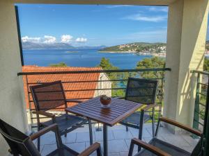 un tavolo e sedie su un balcone con vista sull'acqua di Eco Sunshine Apartments Lumbarda a Lumbarda (Lombarda)