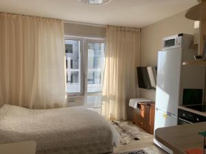a bedroom with a bed and a refrigerator and a window at Max House in Barnaul