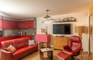 sala de estar con sofá rojo y cocina en Domaine du Parc 101B, en Leysin