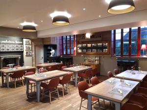 een restaurant met tafels en stoelen en een open haard bij Logis hôtels Auberge du Château in Saint-Rémy-de-Blot