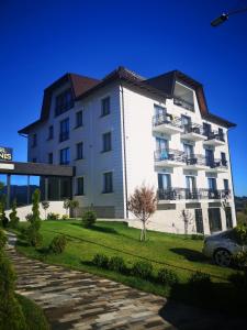 - un grand bâtiment blanc avec une voiture garée à côté dans l'établissement Adonis 201, à Zlatibor