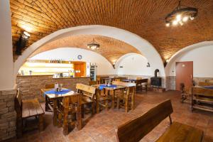 a restaurant with wooden tables and chairs and a brick wall at Penzion Rozhovice in Rozhovice