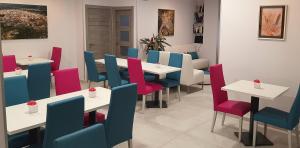 un comedor con mesas blancas y sillas coloridas en Hotel Avenida Plaza en Alzira