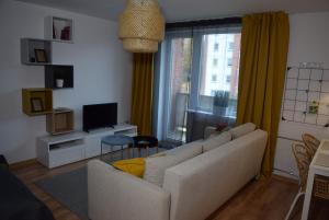 a living room with a couch and a television at Sun apartments in Anykščiai