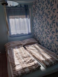 uma pequena cama num quarto com uma janela em Jómadarak Nyaralója em Veresegyház