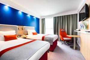 a hotel room with two beds and a desk at Holiday Inn Express London Stansted Airport, an IHG Hotel in Stansted Mountfitchet