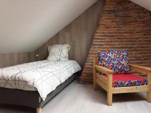 a bedroom with a bed and a chair with a brick wall at Les Billardes - le gite - Jura in Gizia