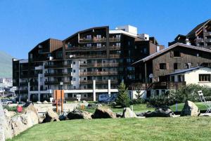 a large building with rocks in front of it at Residence Le Christiana - maeva Home in La Tania +3 photos