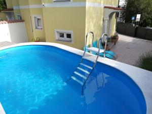 una piscina azul con 2 sillas azules junto a un edificio en Villa Chiara en Dramalj
