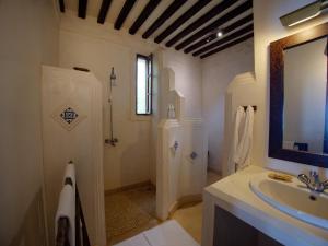 a white bathroom with a sink and a mirror at Peponi Hotel Lamu - Kenya in Shela