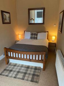 a bedroom with a bed with a mirror and two lamps at Roy Place Gdn Apartment in Campbeltown