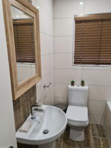 a white bathroom with a toilet and a sink at Villa Casa Lifestyle in Nelspruit