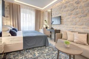 um quarto de hotel com uma cama e um sofá em Heritage Hotel Leon Coronato em Perast