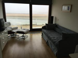 a living room with a couch and chairs and a large window at prachtige studio met havenzicht in Ostend