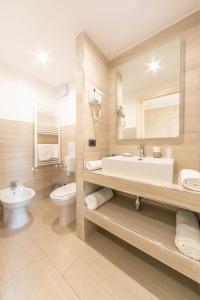 uma casa de banho com um lavatório, WC e um espelho. em Gold Hotel em Bordighera