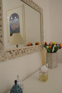 een spiegel aan een muur naast een vaas met bloemen bij Cuore di Vieste in Vieste