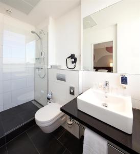 biała łazienka z umywalką i toaletą w obiekcie Webers - Das Hotel im Ruhrturm, Stefan Weber GmbH w Essen