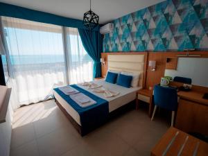 a bedroom with a bed and a desk and a window at Pearl Beach Hotel & Resort in Čanj