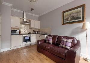 een woonkamer met een bruine leren bank in een keuken bij Ladystairs 1 Royal Mile in Edinburgh